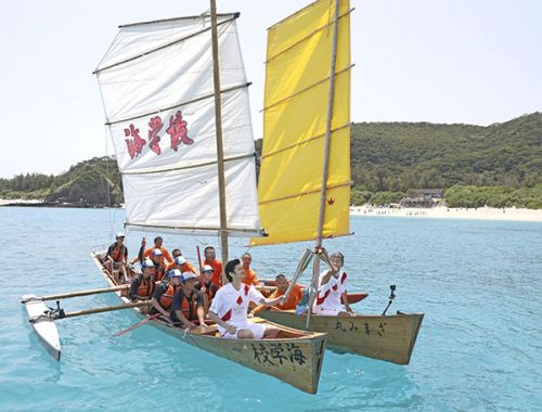 The Olympic torch races through the Kerama blue sea aboard a sabani boat paddled by Zamami middle schoolers